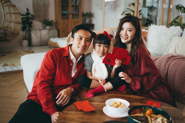 A family with a child holding a handful of red packets or lai see.